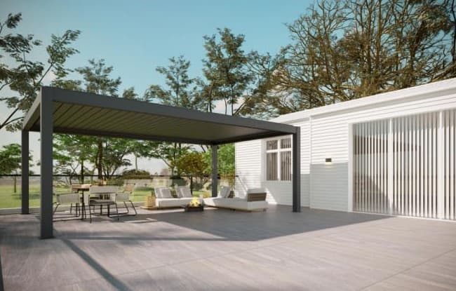 Pérgola negra de gran formato junto a una casa, con living y comedor exterior